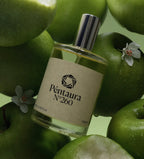 A bottle of Péntaura N°260 perfume surrounded by green apples, with a beige label and a silver cap.