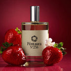 A bottle of Péntaura N°258 perfume centered against a deep red background, surrounded by three fresh strawberries and a small white flower. The bottle has a clear glass body, a silver cap, and a cream label with black text.