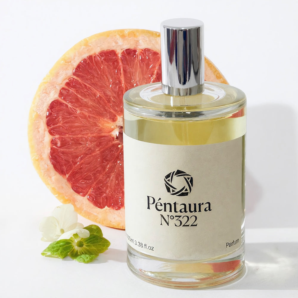A bottle of Péntaura N° 322 perfume with a silver cap and cream label, styled with a sliced grapefruit and small white flowers on a clean white background.