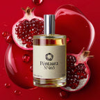 A bottle of Péntaura N° 465 perfume centered on a vivid red background, surrounded by glossy red liquid pools and cut pomegranate halves. The bottle has a silver cap and a cream label with black text.