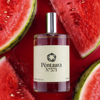 A clear glass perfume bottle with a silver cap and a cream label reading 'Péntaura N°571' is centered against a glossy red background surrounded by watermelon slices. The product appears to be a fragrance, and the watermelon imagery suggests a watermelon scent story.